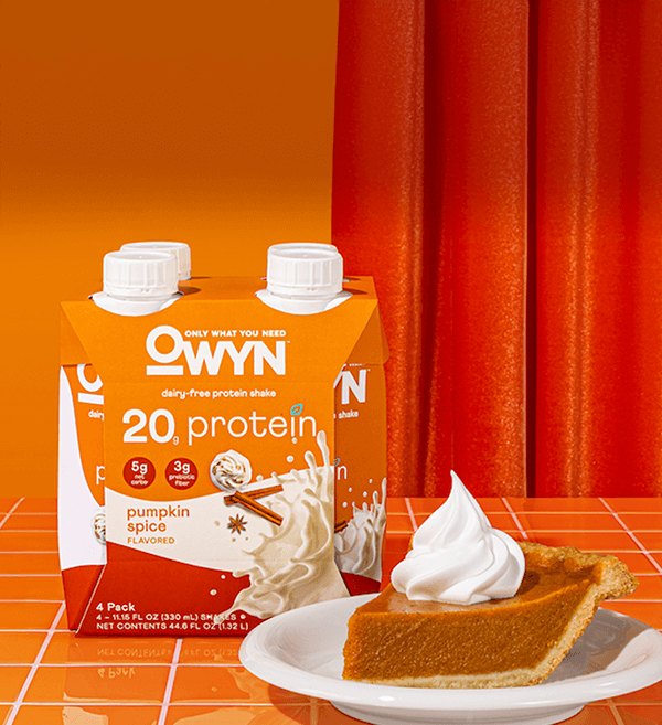 Owyn pumpkin spice flavored protein drink with pumpkin pie on a plate with orange color background