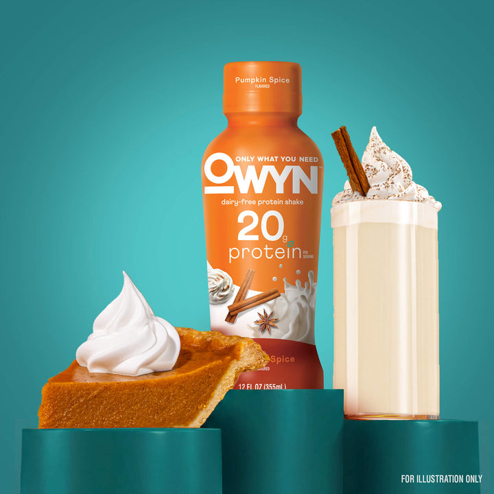 An orange bottle of OWYN Pureskin Spice protein shake stands on a teal pedestal, flanked by a slice of pumpkin pie with whipped cream and a milkshake topped with whipped cream and cinnamon sticks against a teal background.