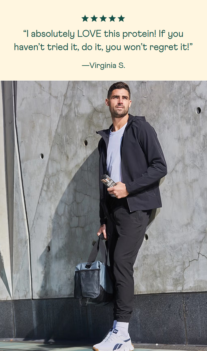 A man holding an Owyn protein shake with a positive review quote on a gray wall background. Customer testimonial: "I absolutely love this protein! If you haven't tried it, do it, you won't regret it!" - by Virginia S. Also 